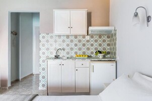 Una cocina compacta con un armario blanco, una pequeña encimera y una lámpara de pared.