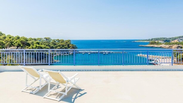 A balcony with white chairs overlooking a coastal view. - Oniro Pension (Alonissos)