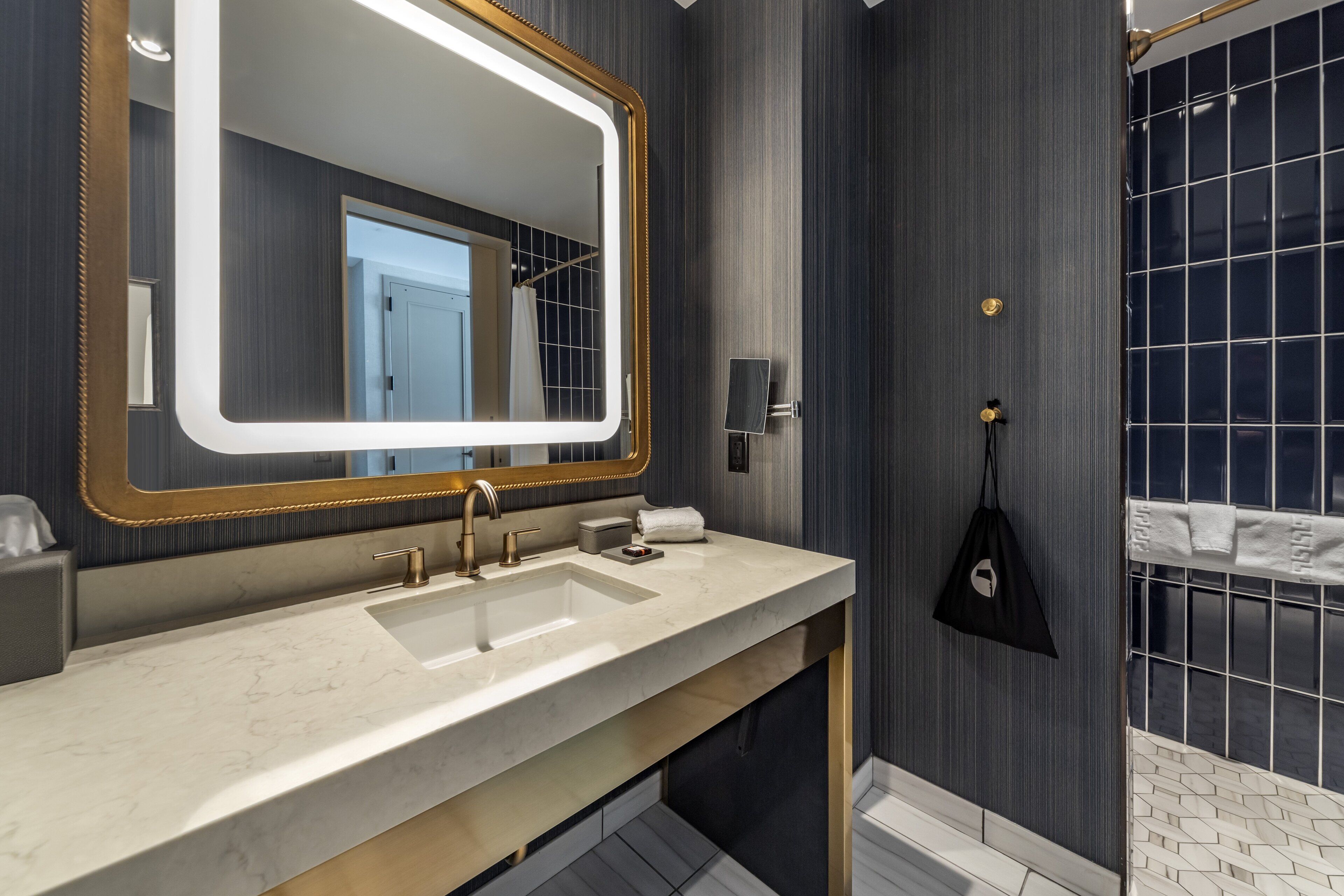 A modern bathroom with a large mirror, dual sinks, and a shower area.