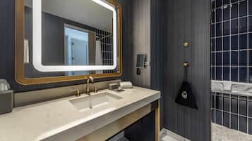 A modern bathroom with a large mirror, dual sinks, and a shower area.