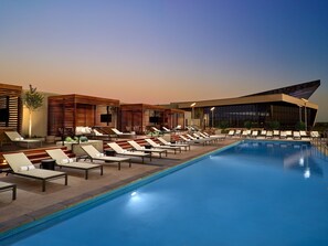 A poolside area with lounge chairs and a modern building with large windows. - Omni Oklahoma City Hotel (Oklahoma City)