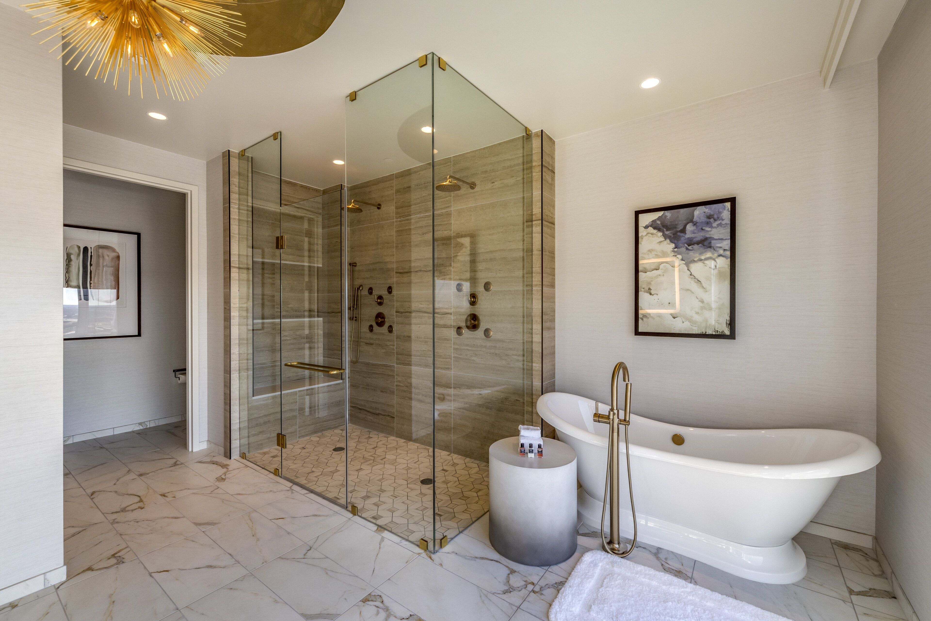 Une salle de bain moderne dotée d’une douche à parois de verre, d’une baignoire sur pieds et d’un sol en marbre.
