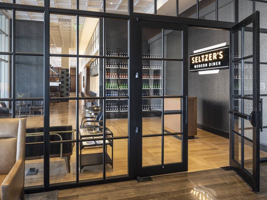 A modern diner interior with a glass door entrance, seating area, and a visible bar.