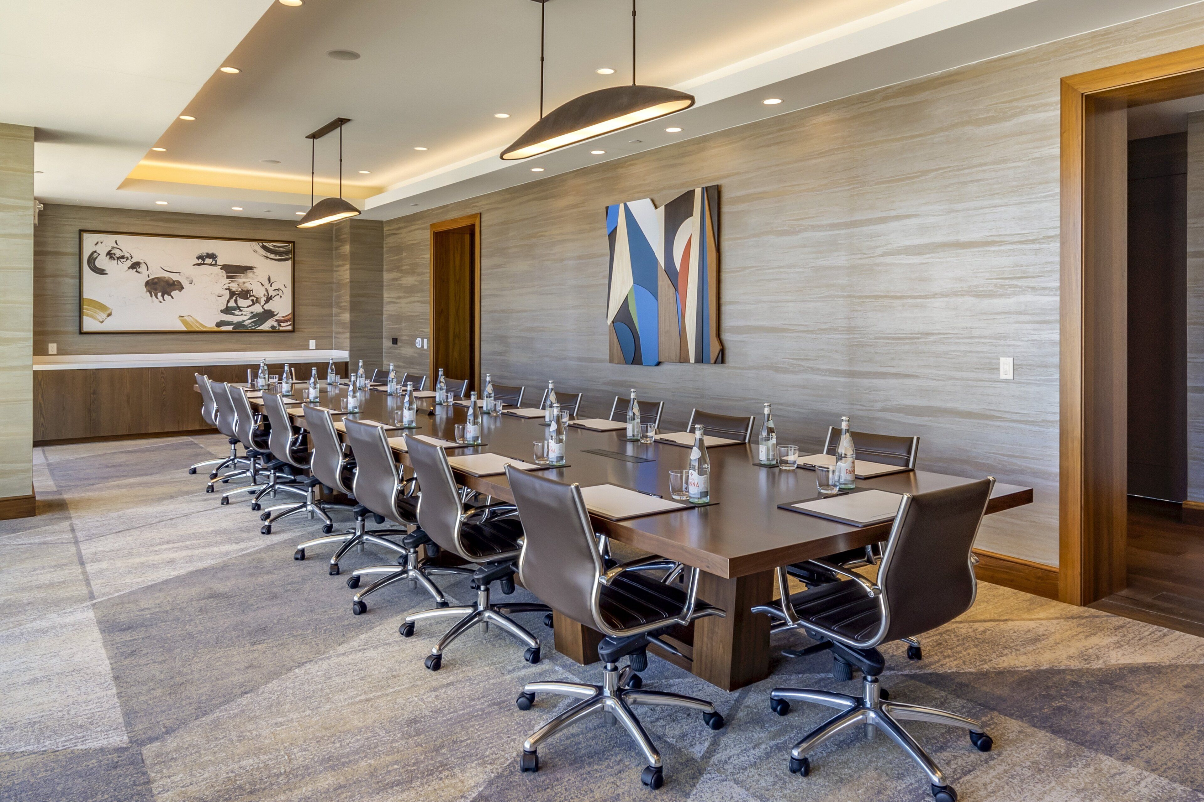 A conference room with a long table, multiple chairs, and water bottles.