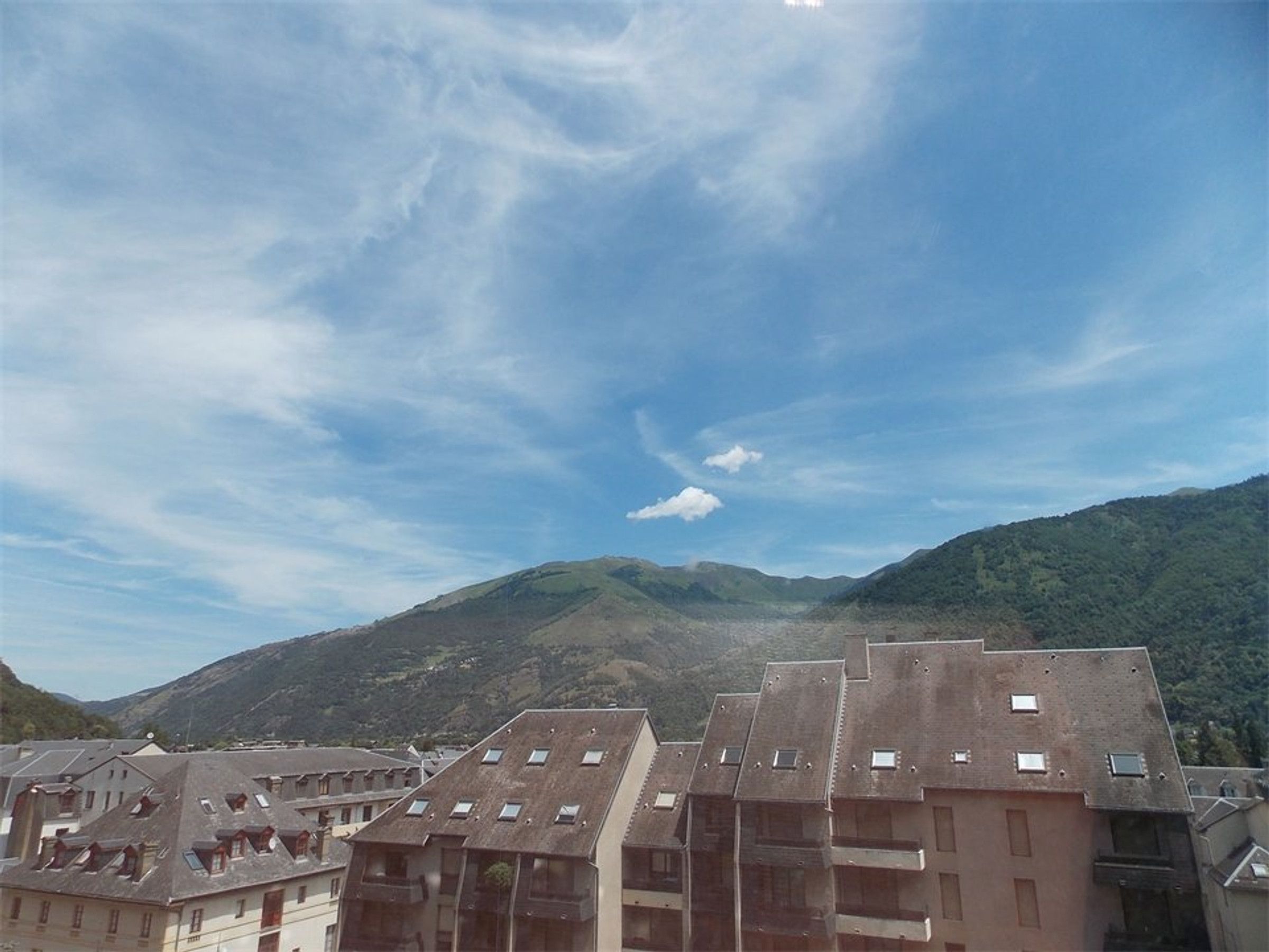 A residential area with multi-story buildings, some with visible balconies, under a partly cloudy sky.