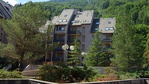 A multi-story building with a flat roof, surrounded by trees and a mountain in the background. - Duplex T3 in Luchon - 6 pers, cable car, parking, wifi (Bagnères-de-Luchon)