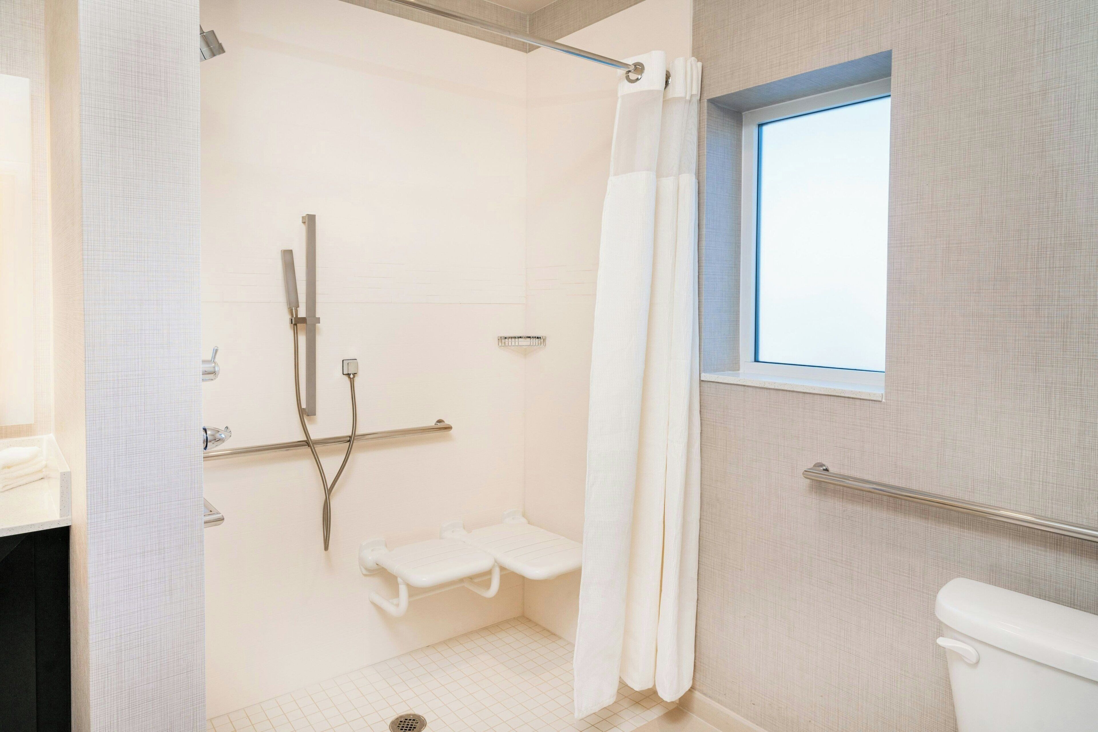 A bathroom with a shower, toilet, and window.