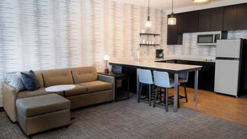 A modern kitchen with a built-in microwave, a refrigerator, and a dining area with a small table and chairs.
