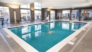 Una piscina interior con agua cristalina, rodeada de sillones de descanso y una tumbona.