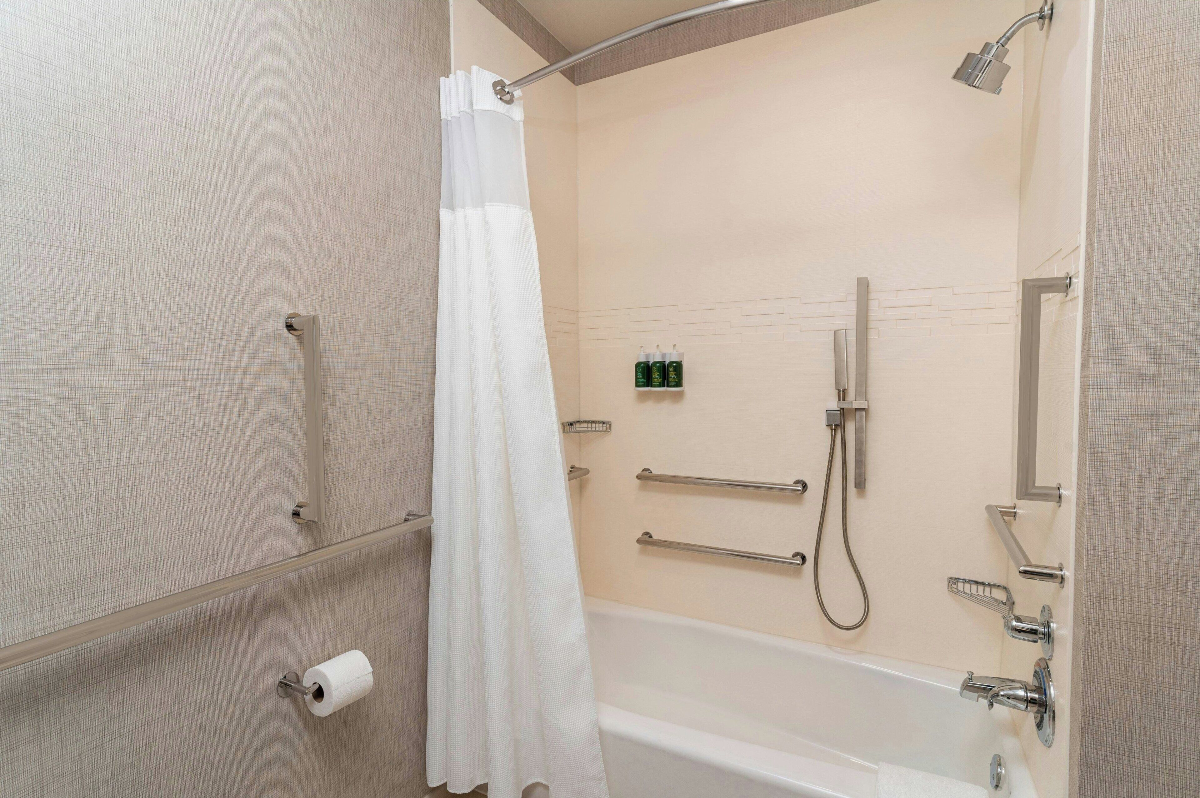 Un baño con bañera, ducha, toallero, papel higiénico y cortina de ducha.
