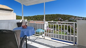 En balkon med et bord, stole og en skål med frugt.