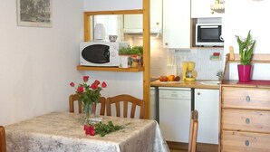Une table à manger ornée d’un vase de roses rouges, de chaises en bois et d’une nappe blanche.
