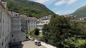 Un immeuble à plusieurs étages doté d’une cour intérieure, entouré de collines verdoyantes.