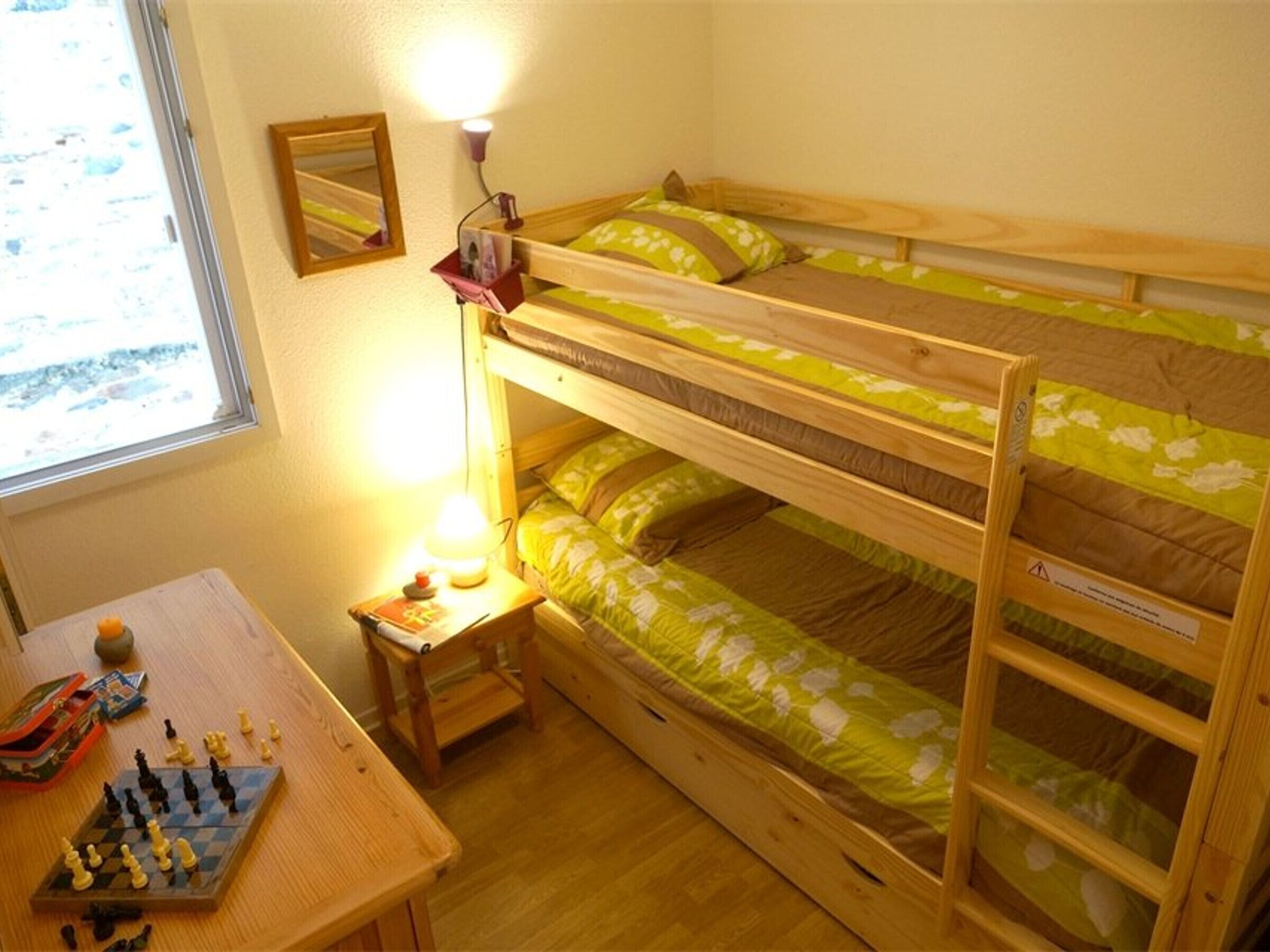 A bunk bed room with a chessboard on a wooden table.