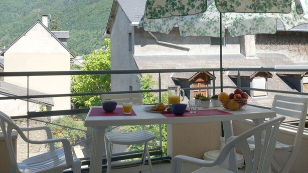 A balcony with a table set for breakfast, overlooking a mountainous landscape. - Near Thermal Baths - T2 with Balcony, Parking and WiFi - Pets Allowed (Bagnères-de-Luchon)