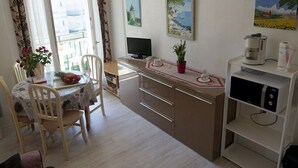Cocina compacta con comedor, televisor y cafetera.
