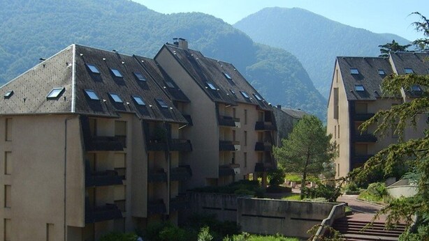A residential building with multiple balconies and a sloped roof. - Luchon: Central Apt - Garage, Balcony, 4 Guests, Near Lift & Thermal Baths (Bagnères-de-Luchon)