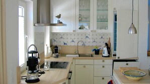 A kitchen with white cabinets, a stainless steel range hood, a coffee maker, a kettle, and a sink. - Windrose, Deutschland (Breege)