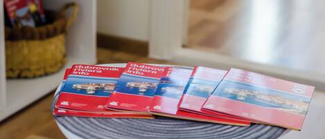 Une pile de brochures est posée sur une table ronde, avec un panier en osier en arrière-plan.