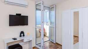 A room with a TV, a desk with binoculars, a wardrobe, and a sliding glass door leading to an outdoor area. - Apartment Vedrana (Dubrovnik)