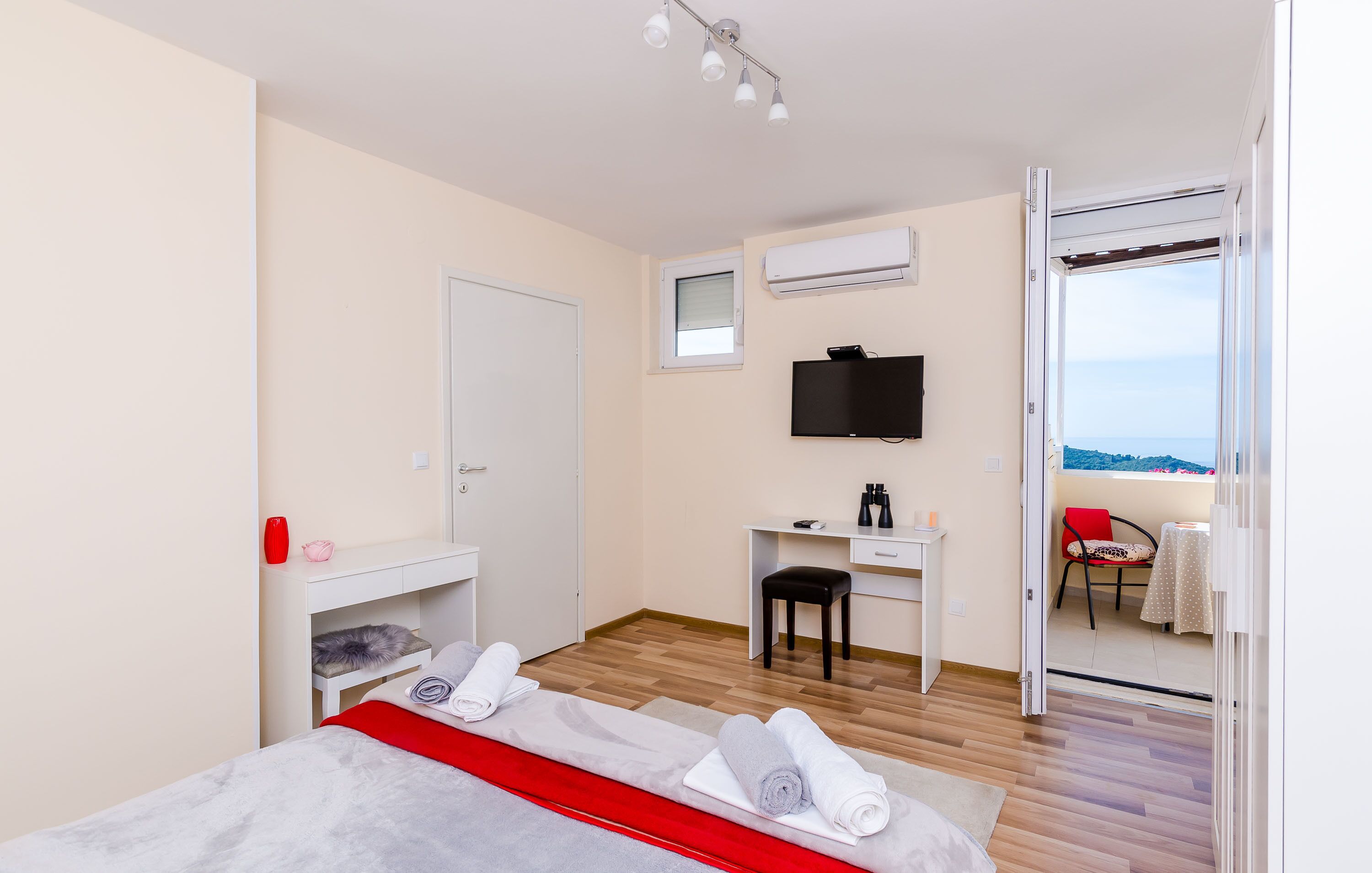 A bedroom with a bed, a desk, a chair, and a TV.