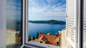 A view from a window overlooking a body of water with buildings in the background. - Apartment Vedrana (Dubrovnik)