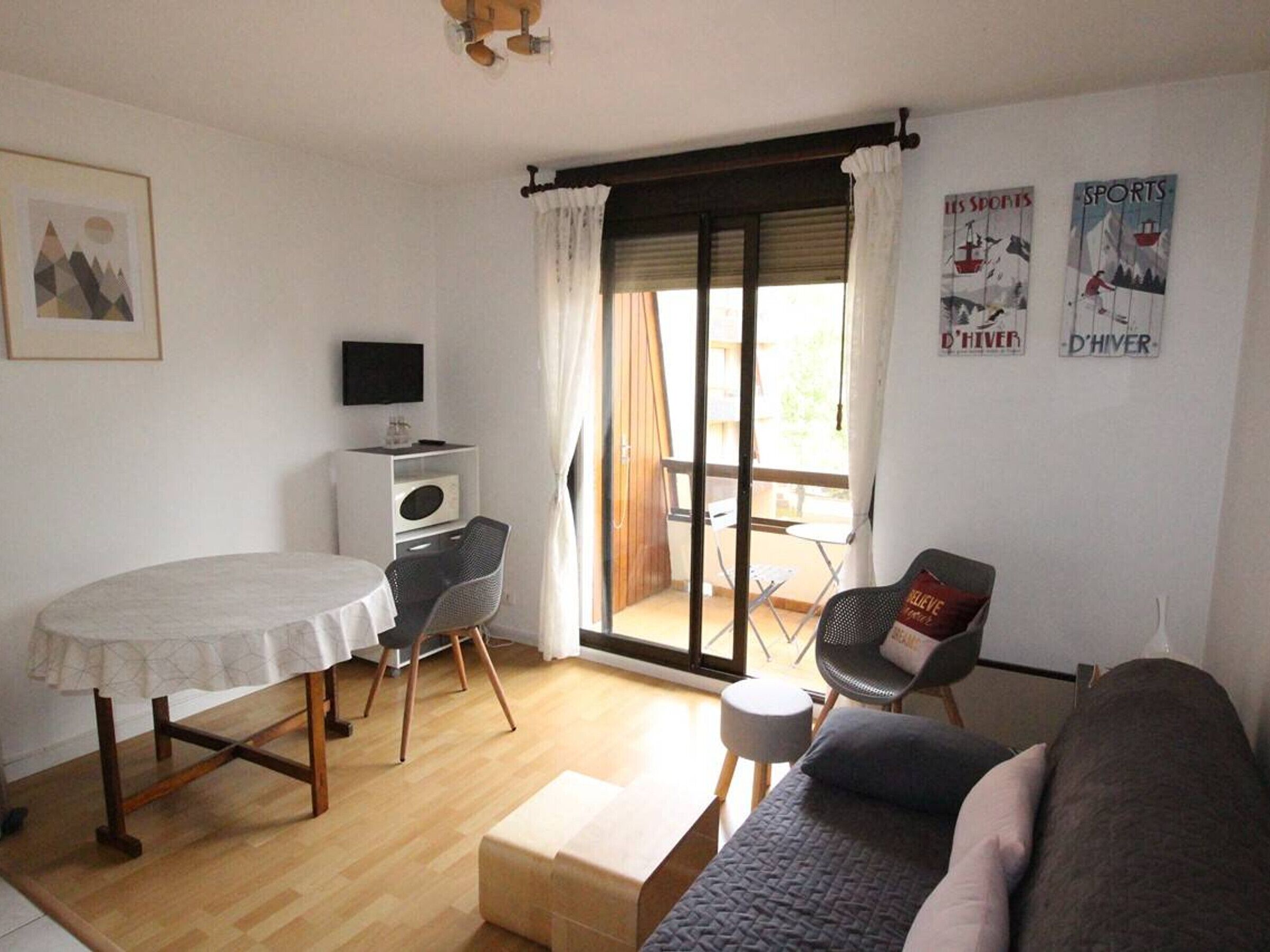 A cozy living room with a sofa, a small table, a TV, and a window with curtains.