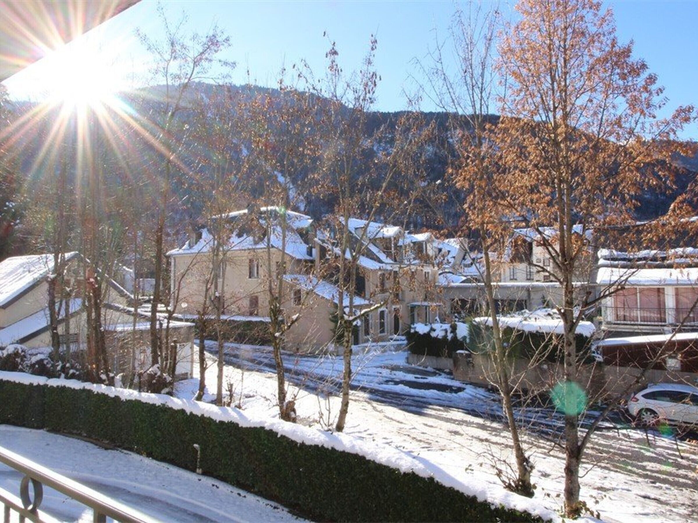 A residential area with houses covered in snow, a clear sky, and a sun shining.