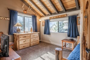 Um quarto aconchegante com cômoda de madeira, televisão e escrivaninha com abajur.