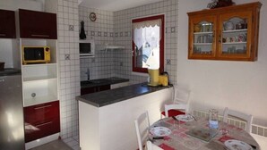 A compact kitchen with a central island, white cabinets, a microwave, and a sink.