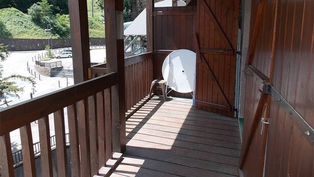 A wooden balcony with a white chair and a satellite dish.
