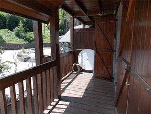 A wooden balcony with a white chair and a satellite dish.