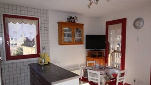 A compact kitchen with a dining area, a TV, and a view of the city.