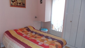 A bedroom with a bed, a window, a door, and a painting on the wall.
