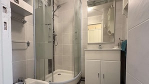 Une salle de bain moderne avec une douche à parois de verre, un lavabo blanc et un meuble de rangement.