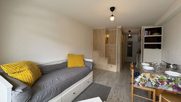 Un espace de vie compact comprenant un canapé, une table à manger et un coin cuisine.