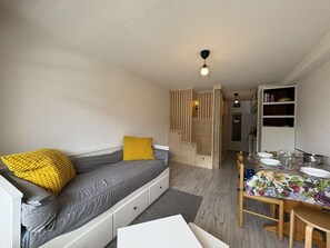A compact living space with a sofa, a dining table, and a kitchen area.