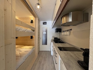 A compact kitchen with a wooden floor, a sink, a stove, and a microwave.