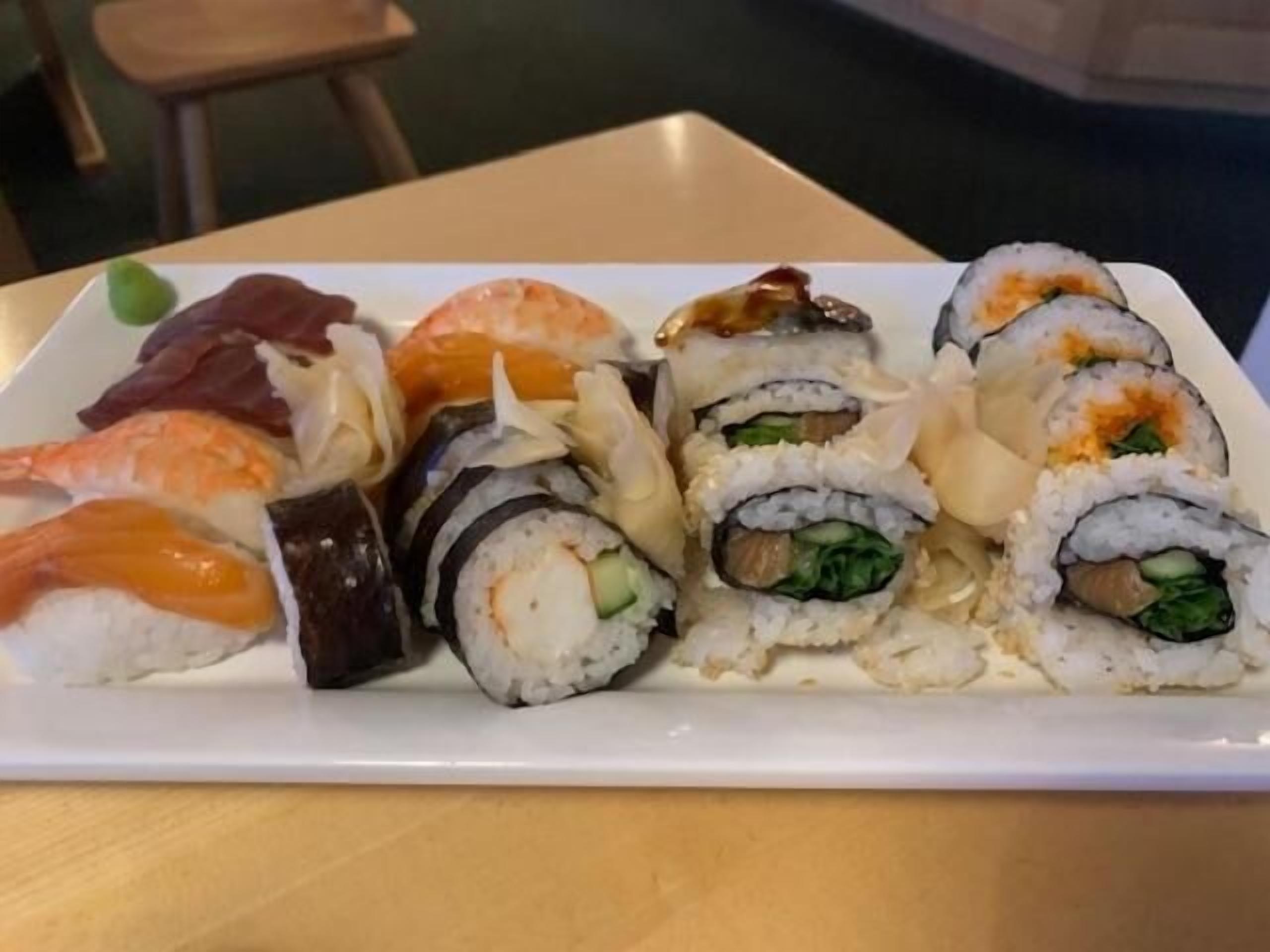 Un plato de sushi con diferentes variedades, incluyendo camarones, salmón y rollos con verduras.