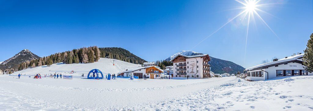 Une station de ski enneigée, avec des bâtiments, dont un chalet et un restaurant, et un télésiège en arrière-plan.