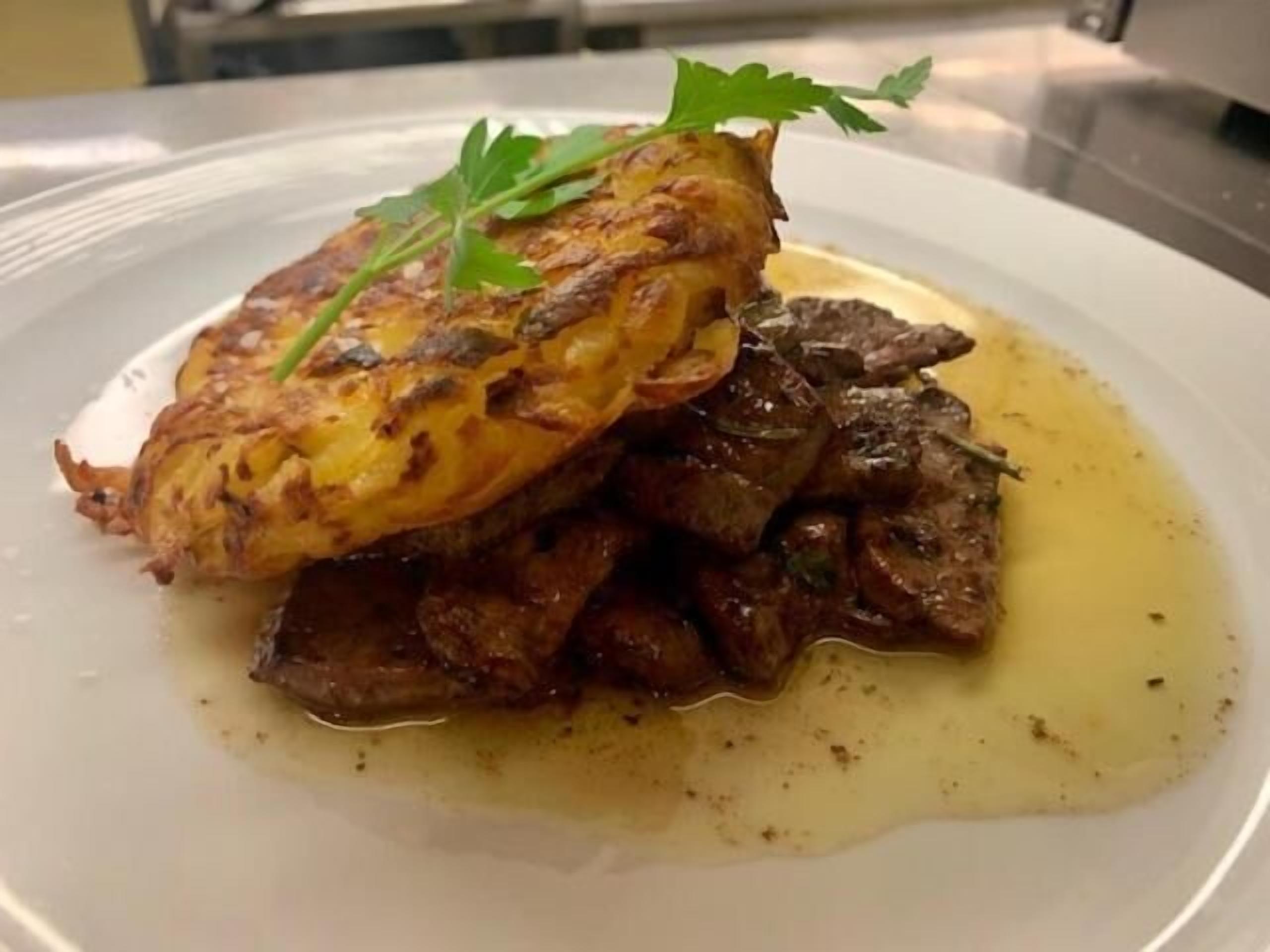 A plate of food with a golden-brown crust, meat, and a garnish of green leaves.
