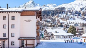 A hotel named "Hotel Bünna Restaurant" with a view of snow-covered mountains and a ski slope in the background. - Hotel Bünda Davos (Davos)