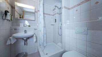 Een moderne badkamer met een wastafel, spiegel, douche en toilet.