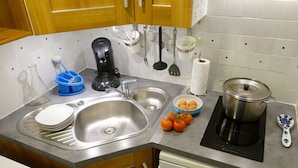 A kitchen with a sink, stove, and various utensils.