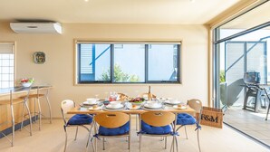 Un comedor con un amplio ventanal, zona de cocina y una parrilla al aire libre.