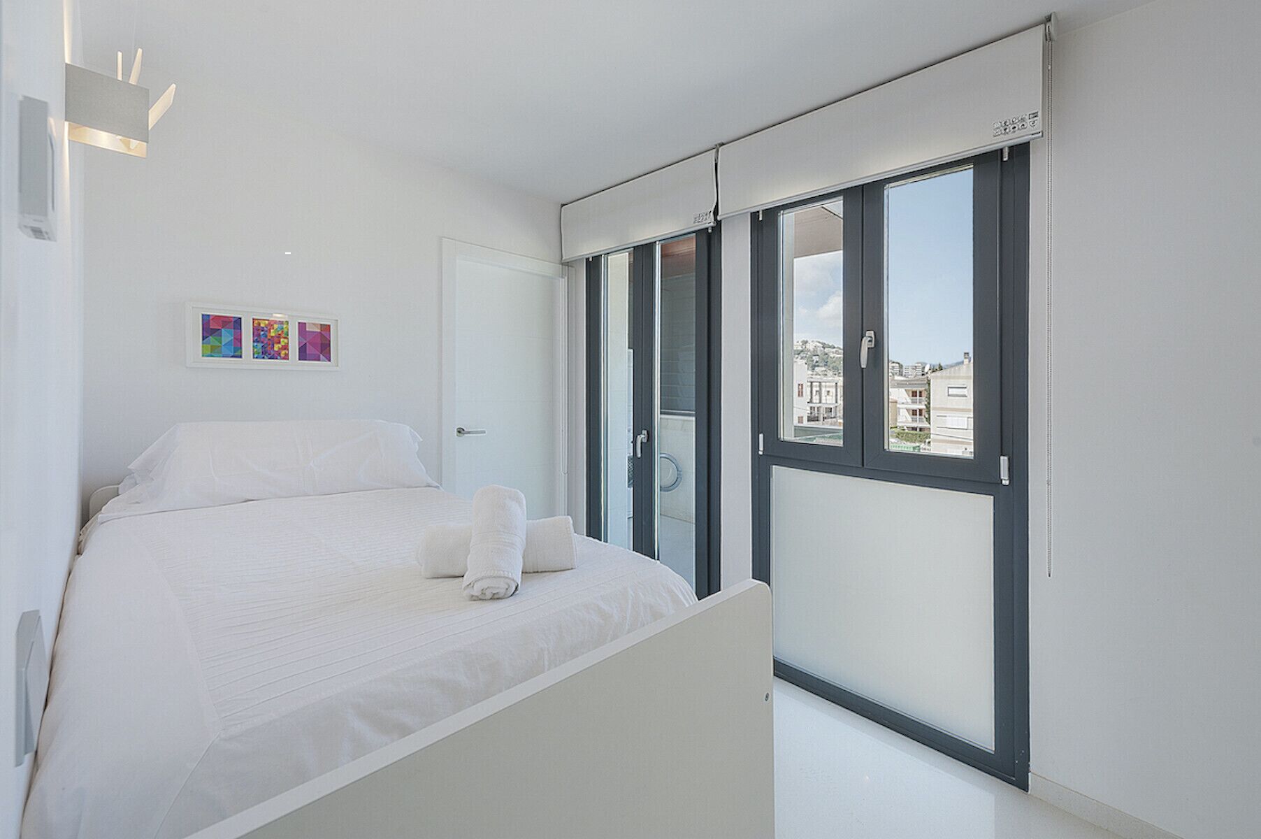 Een moderne slaapkamer met een bed, een raam en een deur.
