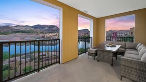 Un balcon avec vue sur les montagnes et une rivière, aménagé avec un canapé et une table.