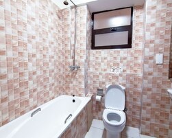 Un baño con bañera, inodoro y zona de ducha.