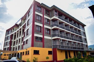 Un hotel de varios pisos con un diseño moderno, que cuenta con balcones en cada planta y un techo plano.