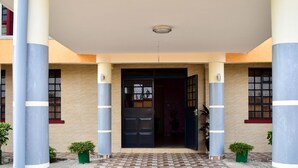 A building entrance with a tiled pavement, large columns, and potted plants. - Divine Homes Resort (Kisumu)